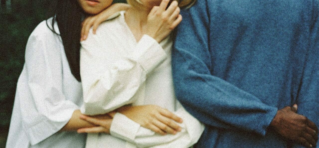 three people holding onto one another